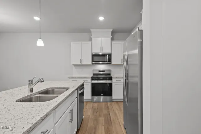 a kitchen with kitchen island granite countertop a sink a center island and stainless steel appliances