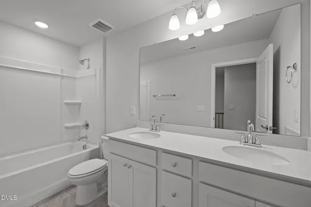 a bathroom with a toilet a sink a tub and a mirror