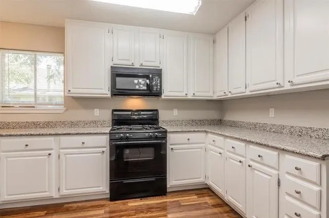 a kitchen with granite countertop white cabinets and a stove