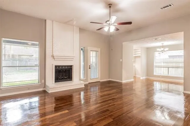 a view of an empty room with wooden floor fireplace and a window