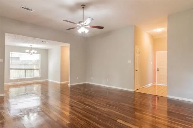 a view of an empty room with wooden floor and a window