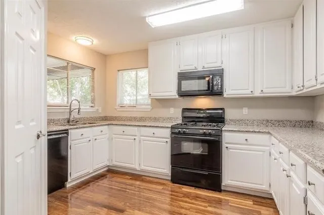 a kitchen with granite countertop a stove a sink and a microwave