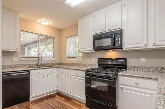 a kitchen with granite countertop cabinets stainless steel appliances and a window