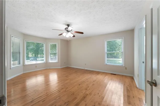 a view of an empty room with window and wooden floor