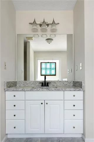 a bathroom with a granite countertop sink a mirror and a bathtub