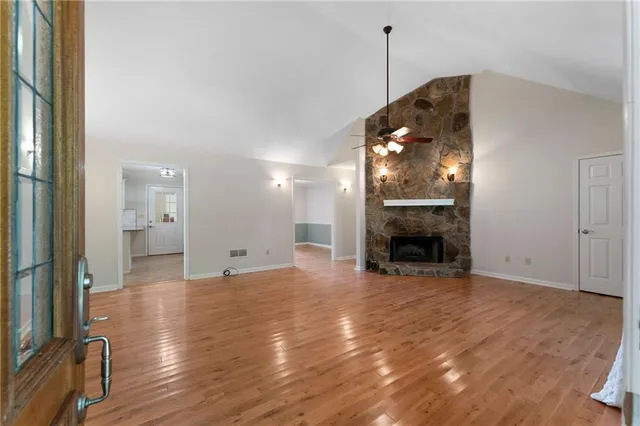 a view of an empty room with wooden floor fireplace and a window