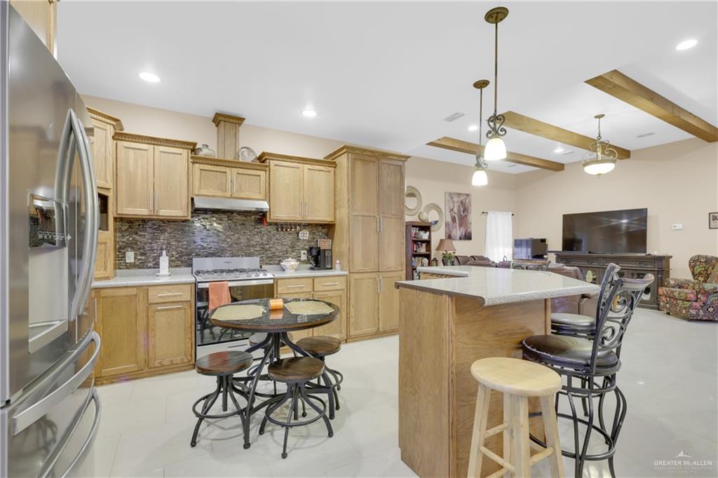 715 North Gonzalez Road Weslaco, TX 78596 - Photo 7 of 31 a kitchen with a table chairs refrigerator and microwave
