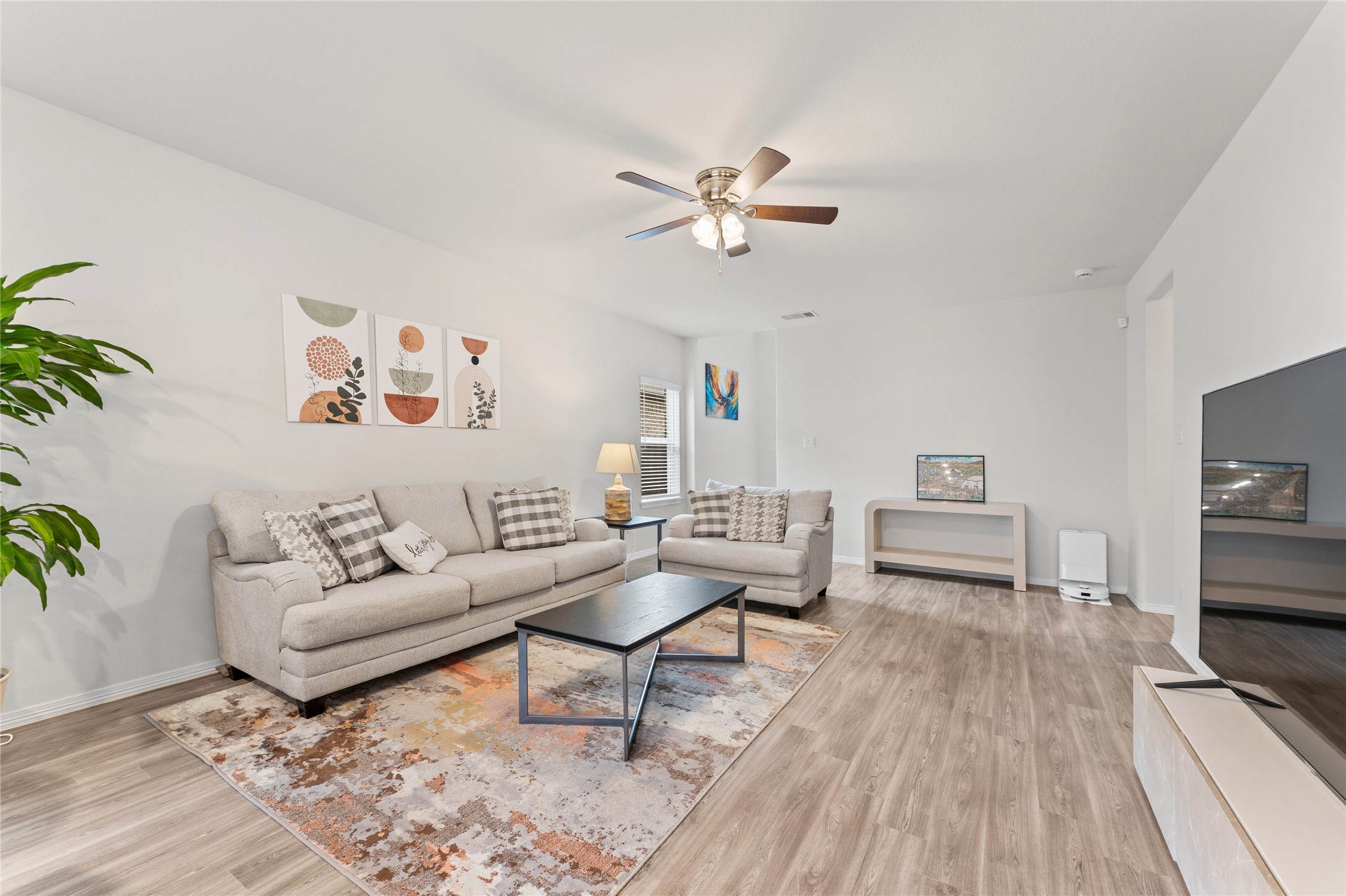 23326 Spring Genesis Lane Katy, TX 77493 - Photo 4 of 32 Stunning wood flooring stretches across the expansive living room, reflecting the abundance of natural light pouring in through wide, picturesque windows.