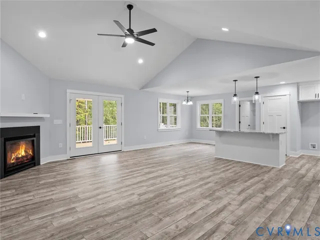an empty room with wooden floor a kitchen view and a window