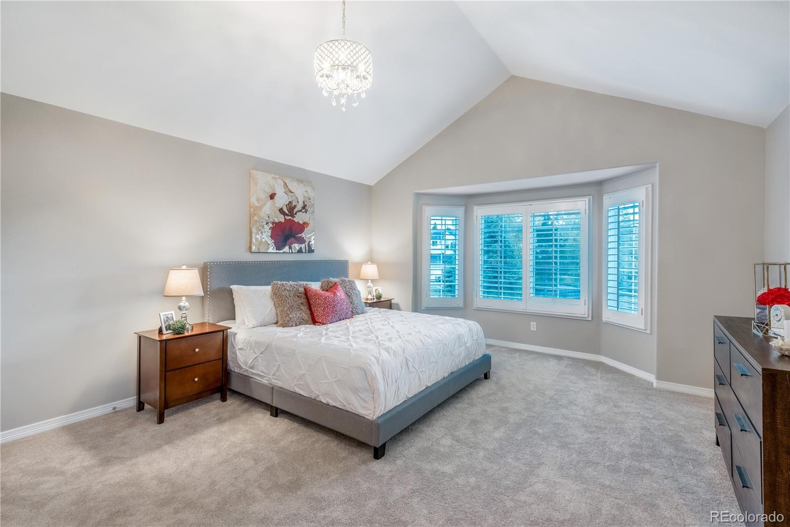 10734 Cougar Ridge Lone Tree, CO 80124 - Photo 10 of 35 a bedroom with a large bed and a chandelier