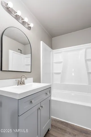 a bathroom with a sink vanity granite tub and a mirror