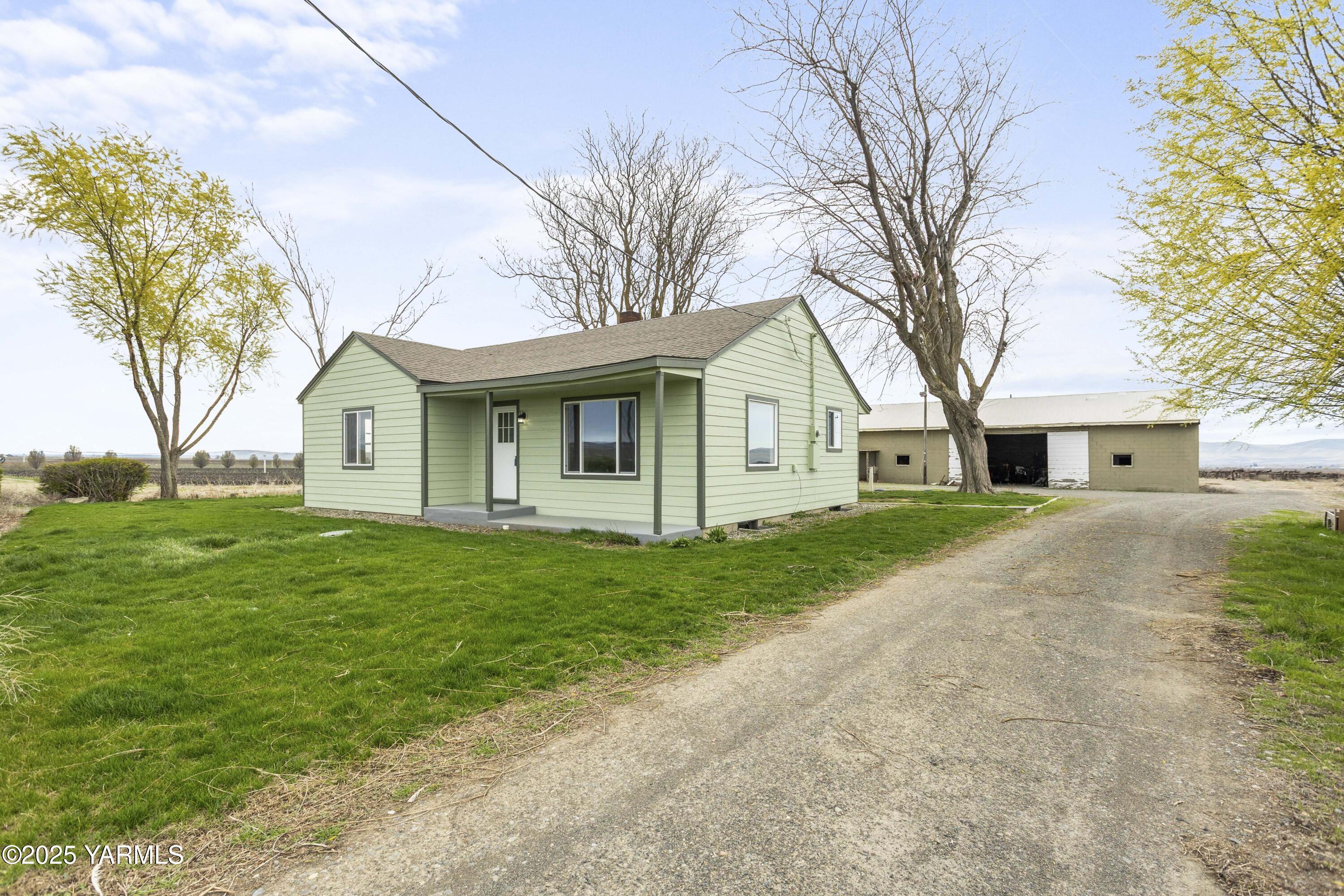 173801 Evans Road Grandview, WA 98930 - Photo 2 of 45 a front view of a house with a garden and trees