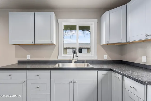 a kitchen with granite countertop white cabinets and a window