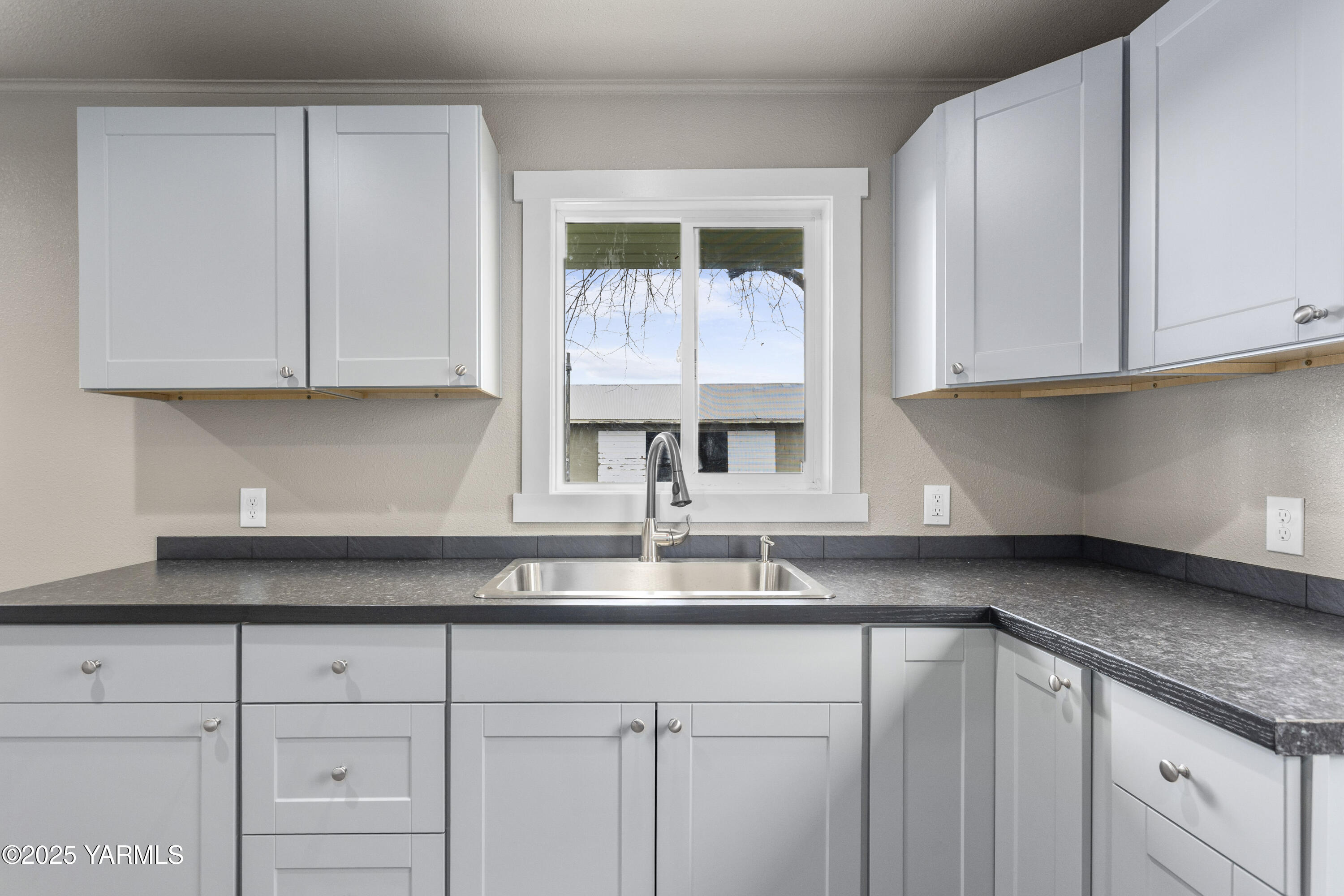 173801 Evans Road Grandview, WA 98930 - Photo 8 of 45 a kitchen with granite countertop white cabinets and a window