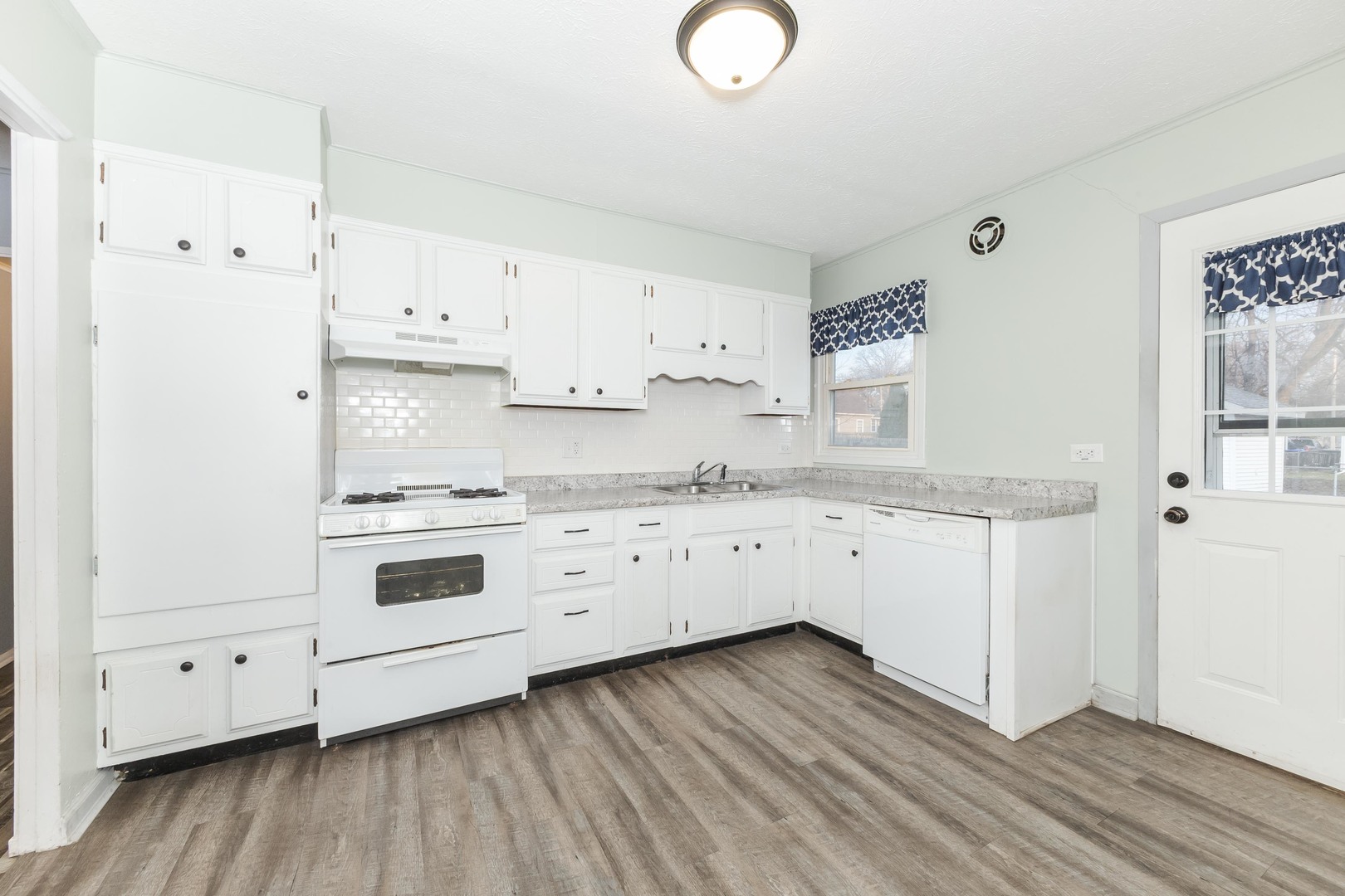334 East Baker Street Bloomington, IL 61701 - Photo 8 of 32 a kitchen with granite countertop white cabinets and white appliances with wooden floor