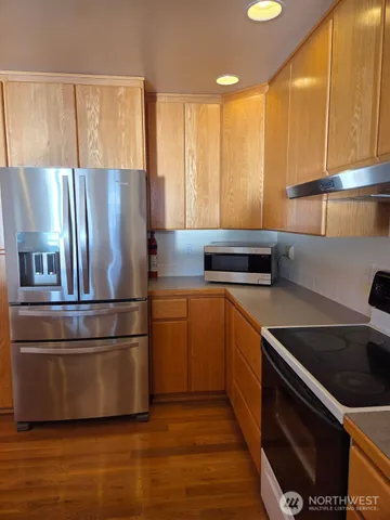 a kitchen with stainless steel appliances granite countertop a refrigerator a sink a stove and a refrigerator