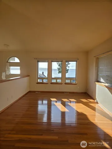 a view of an empty room with window and wooden floor