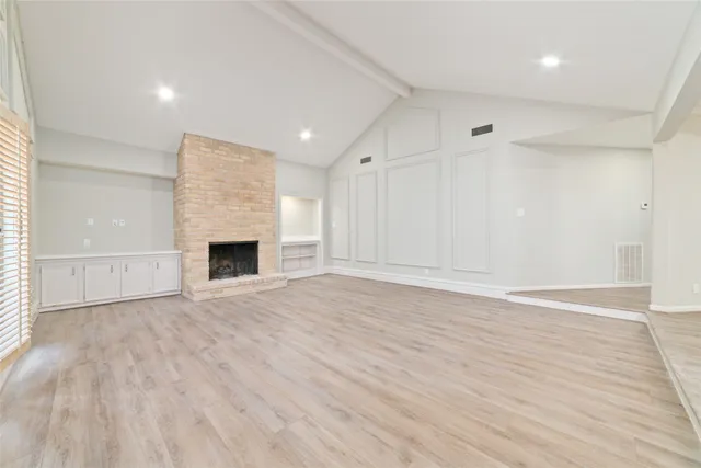 an empty room with wooden floor and fireplace