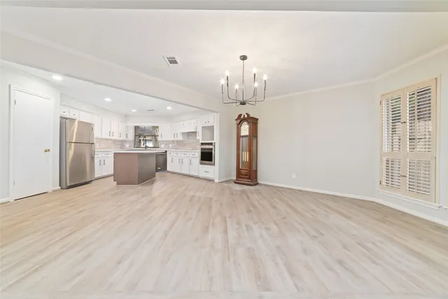 a view of empty room with wooden floor and kitchen view