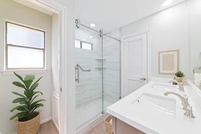 a bathroom with a sink a mirror a potted plant and a shower