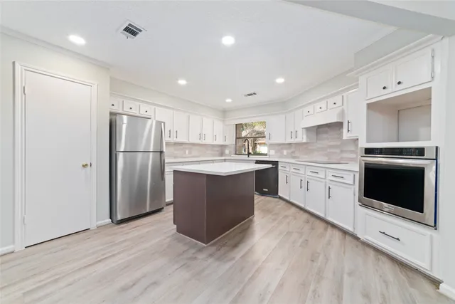 a kitchen with kitchen island a sink stainless steel appliances and cabinets