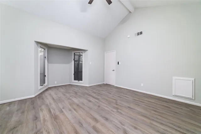 a view of an empty room with wooden floor and closet