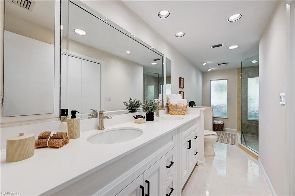 660 14th Avenue South Naples, FL 34102 - Photo 26 of 50 a bathroom with double vanity sinks a vanity two mirror and a shower