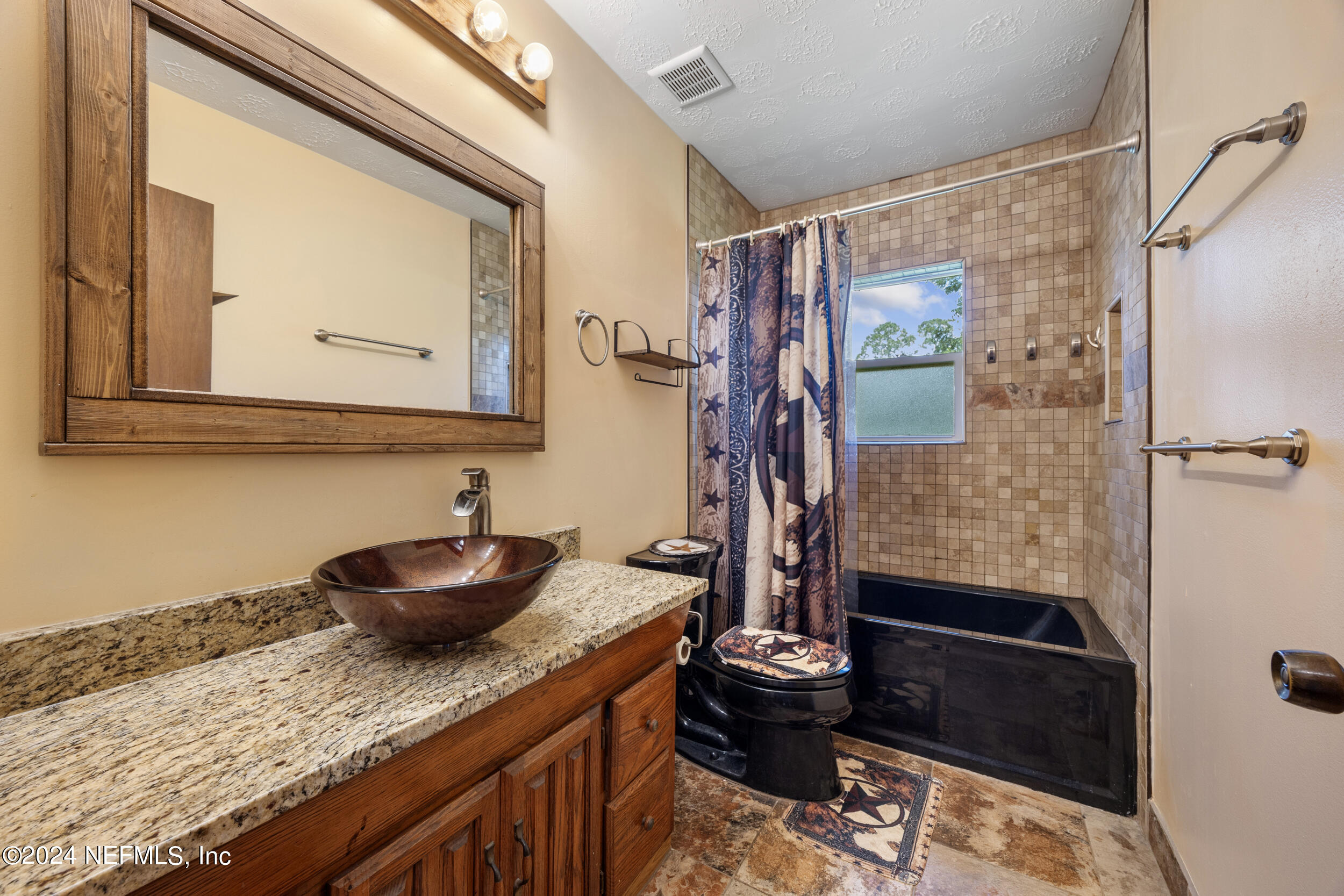 8912 McClelland Road Jacksonville, FL 32234 - Photo 31 of 49 a bathroom with a granite countertop sink a mirror and shower