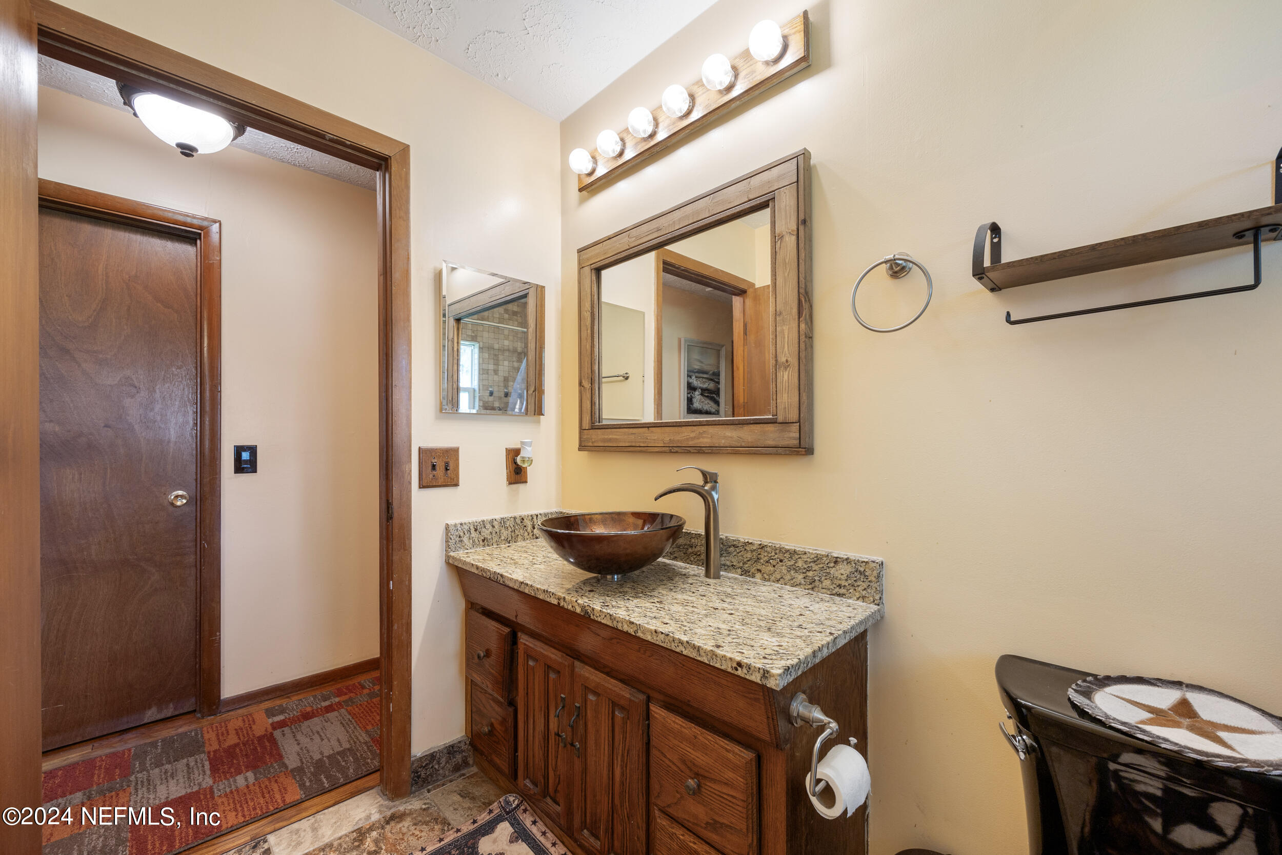 8912 McClelland Road Jacksonville, FL 32234 - Photo 32 of 49 a bathroom with a granite countertop sink and a mirror