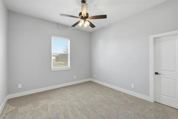 an empty room with a window and a fan