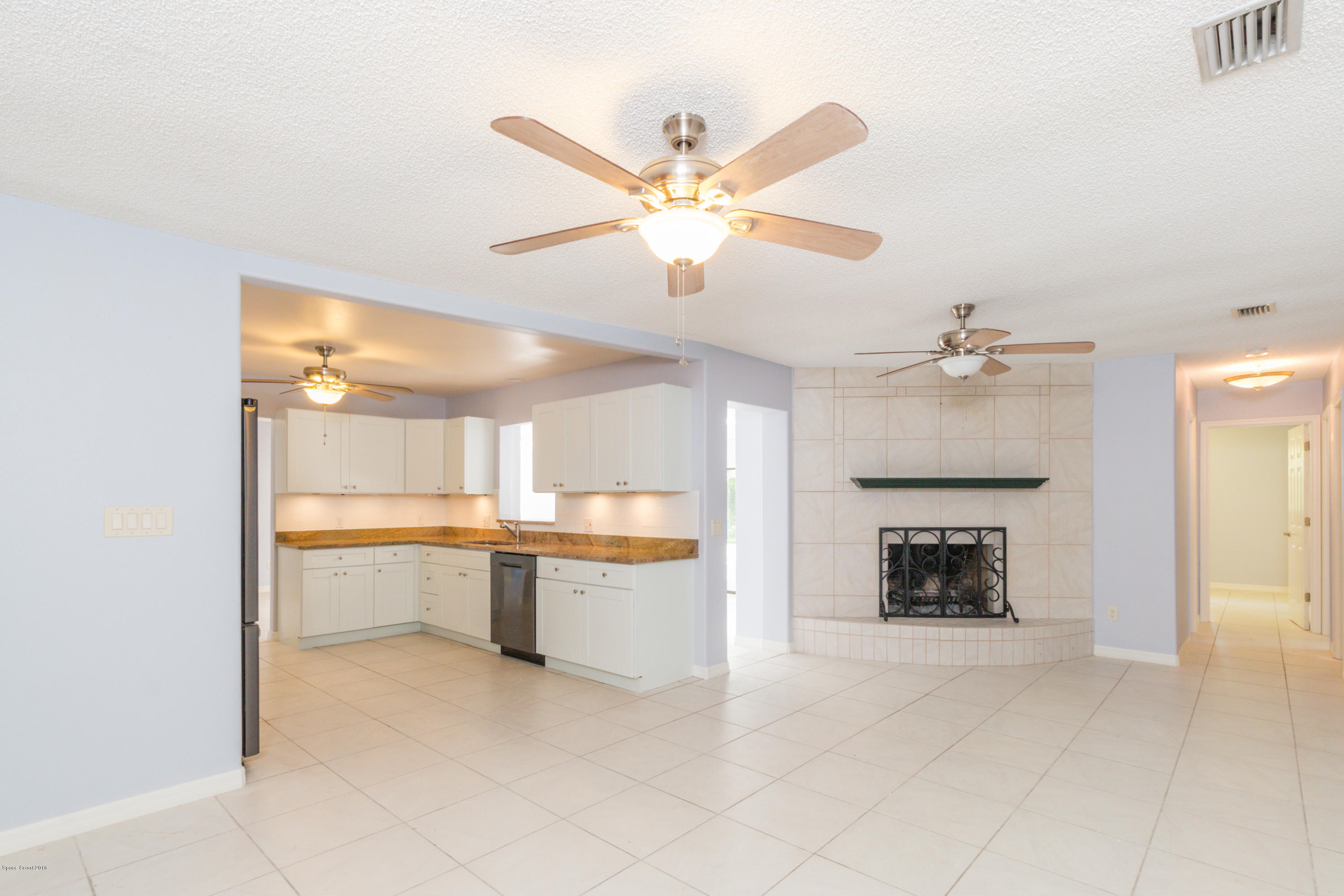 1208 Cimarron Circle Northeast Palm Bay, FL 32905 - Photo 16 of 41 a living room with a fireplace and a ceiling fan