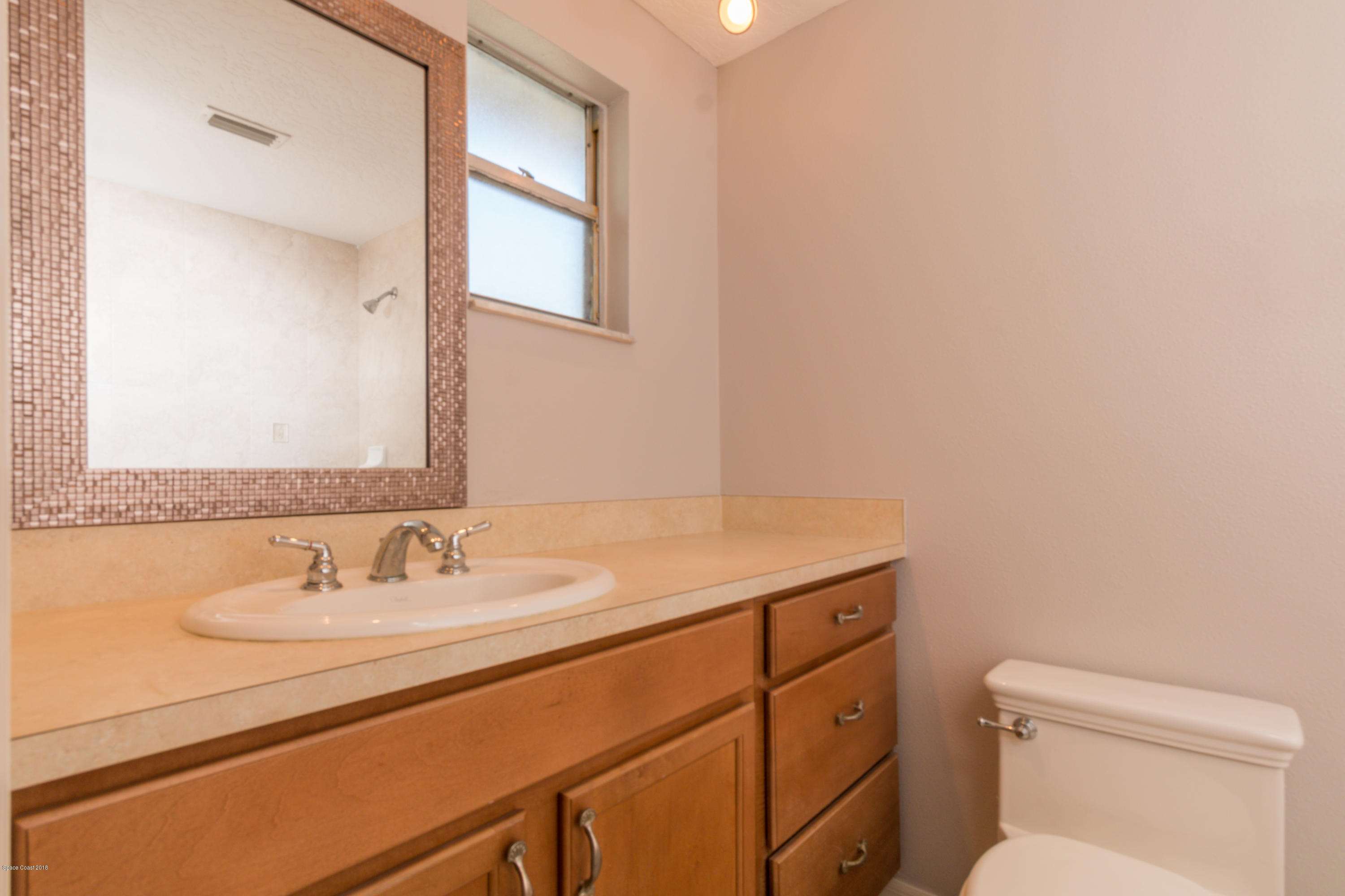 1208 Cimarron Circle Northeast Palm Bay, FL 32905 - Photo 26 of 41 a bathroom with a granite countertop sink a toilet and a mirror
