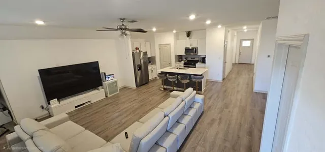 a living room with furniture a flat screen tv and a refrigerator