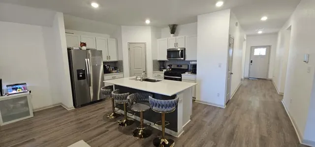 a kitchen with stainless steel appliances a dining table chairs refrigerator and microwave