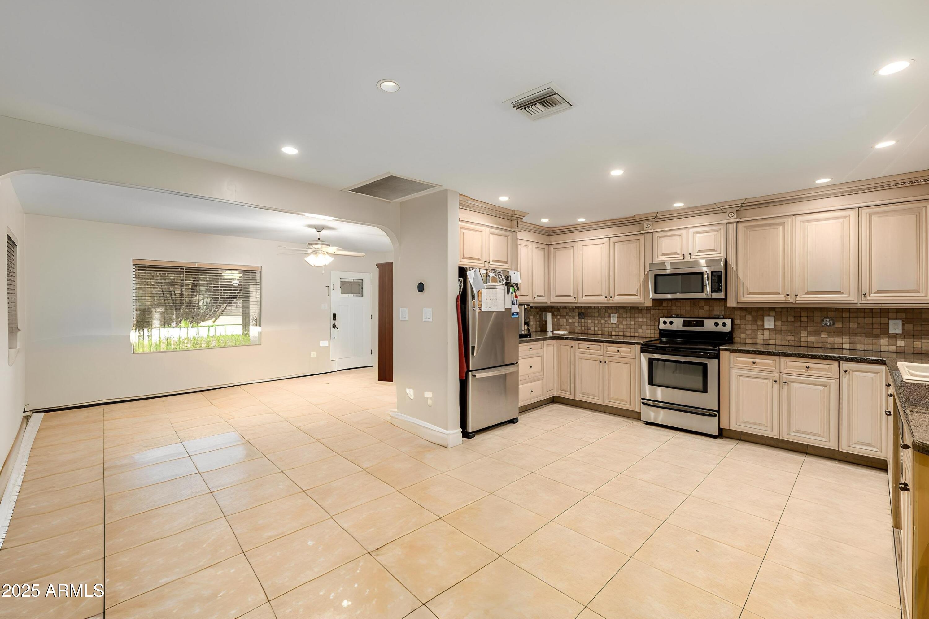 6842 North 10th Place Phoenix, AZ 85014 - Photo 21 of 60 a large white kitchen with stainless steel appliances kitchen island granite countertop a refrigerator and stove top oven