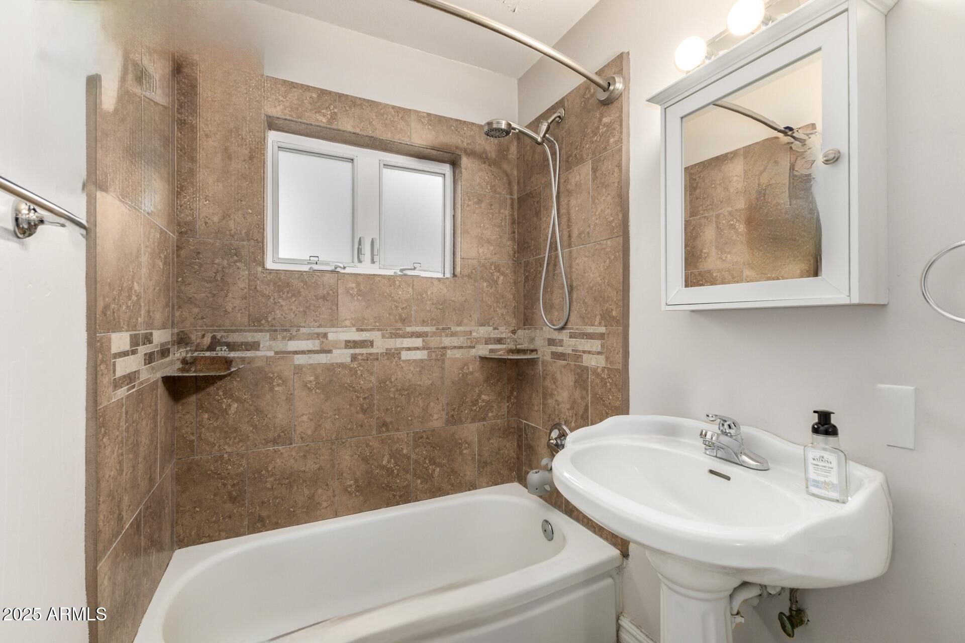 6842 North 10th Place Phoenix, AZ 85014 - Photo 36 of 60 a bathroom with a sink a mirror a bathtub and shower