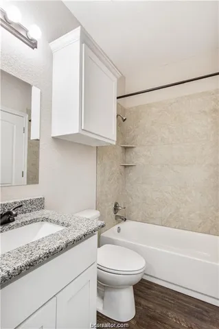 a bathroom with a granite countertop bathtub sink vanity mirror and toilet