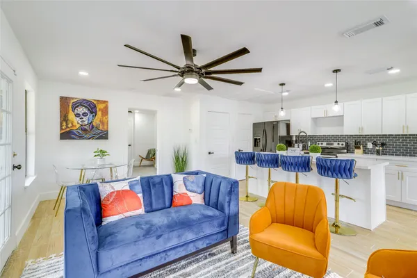 a living room with furniture kitchen view and a chandelier
