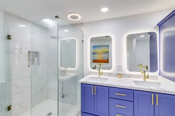a bathroom with double vanity sinks and a shower