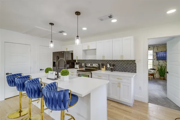 a kitchen with a dining table chairs stainless steel appliances and cabinets