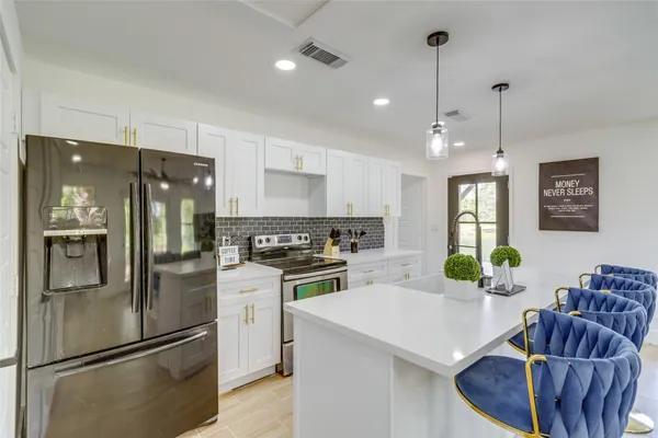 a kitchen with stainless steel appliances granite countertop a refrigerator a sink a stove and a refrigerator