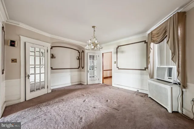 a view of a livingroom with wooden furniture chandelier front door and hallway