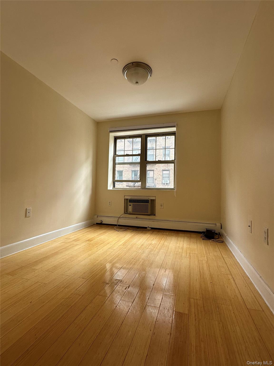 8375 117th Street, Unit 3B Queens, NY 11415 - Photo 5 of 7 an empty room with wooden floor and windows