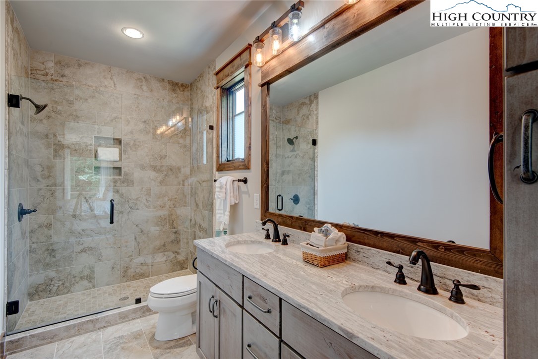 273 High Country Overlook Banner Elk, NC 28604 - Photo 30 of 50 a bathroom with a granite countertop sink toilet a mirror a vanity and shower