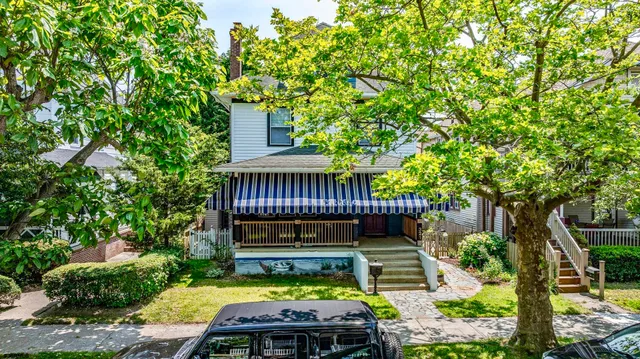 a view of a chair and table in the backyard with large trees