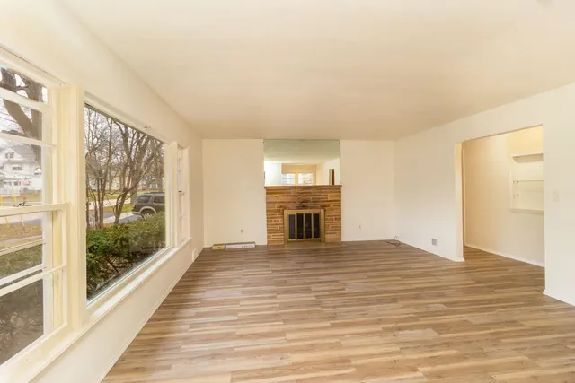 a view of a livingroom with wooden floor and kitchen view