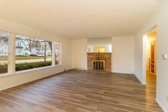 a view of empty room with wooden floor and fireplace