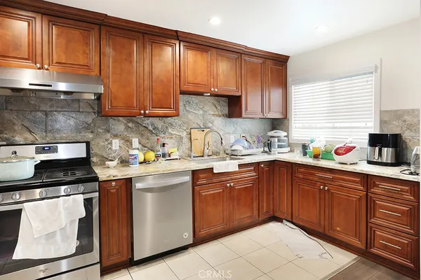 a kitchen with granite countertop wooden cabinets stainless steel appliances and a sink