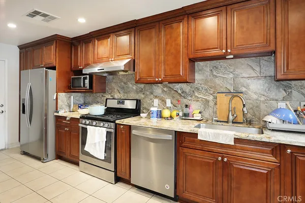 a kitchen with stainless steel appliances granite countertop a stove a sink dishwasher and a refrigerator with cabinets