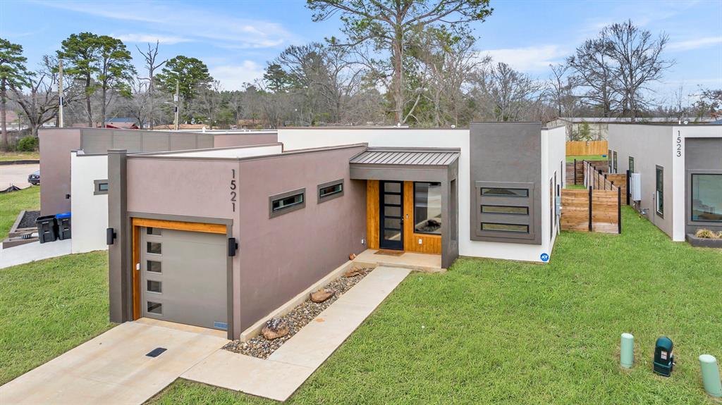 1521 Mahlow Drive Longview, TX 75601 - Photo 1 of 27 Modern home with a front yard, stucco siding, metal roof, an attached garage, and a standing seam roof